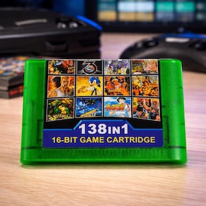 Puede incluir: Un cartucho de juego de 16 bits verde con una etiqueta azul que muestra "138 en 1". El cartucho presenta una cuadrícula de capturas de pantalla de juegos, incluyendo Sonic the Hedgehog y otros títulos clásicos. Un accesorio de juego retro.
