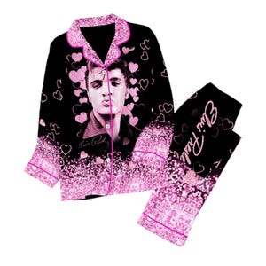 May include: Black pyjama set with a portrait of Elvis Presley surrounded by pink hearts. The set includes a button-down top with pink trim and matching trousers with the text "Elvis Presley".