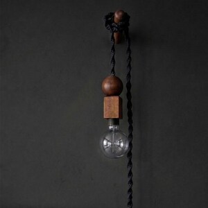 Peut inclure: Suspension luminaire moderne avec une ampoule en verre transparent, une sph&egrave;re et un bloc carr&eacute;s en bois. Le luminaire est suspendu par un cordon torsad&eacute; noir et mont&eacute; sur un mur sombre. Les &eacute;l&eacute;ments en bois ont une finition naturelle et chaleureuse.