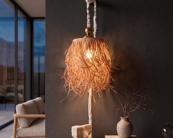 Peut inclure: Une lampe suspendue murale avec un abat-jour en paille frangée brun clair, suspendu par un cordon recouvert de tissu blanc. Le cordon est fixé à un support mural en bois et comporte une pièce d'accent en métal doré au-dessus de l'abat-jour.
