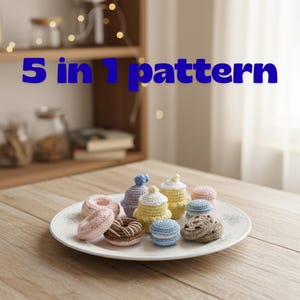 May include: A plate holds a selection of crocheted miniature desserts, such as donuts, cupcakes, and cookies. The text "5 in 1 pattern" is displayed in blue. The handmade items are in pastel colours, with intricate details.