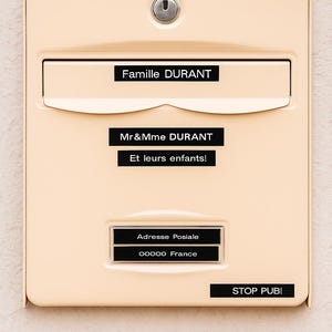 Peut inclure: Une boîte aux lettres beige avec un trou de serrure et plusieurs étiquettes noires. Les étiquettes indiquent "Famille DURANT", "Mr&Mme DURANT", "Et leurs enfants!", "Adresse Postale", "00000 France", et "STOP PUB!".