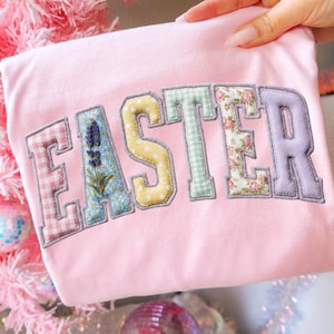 May include: A set of three ceramic mugs with a speckled, matte finish in cream, light grey, and dark grey. Each mug has a simple, minimalist design and a rounded handle. The mugs are stacked on top of each other.