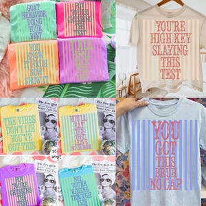 May include: Collection of colorful t-shirts with various phrases printed on them, including "GOAT BEHAVIOR DOING YOUR BEST" and "YOU GOT THIS BRUH NO CAP." The shirts are in shades of pink, orange, yellow, and blue.