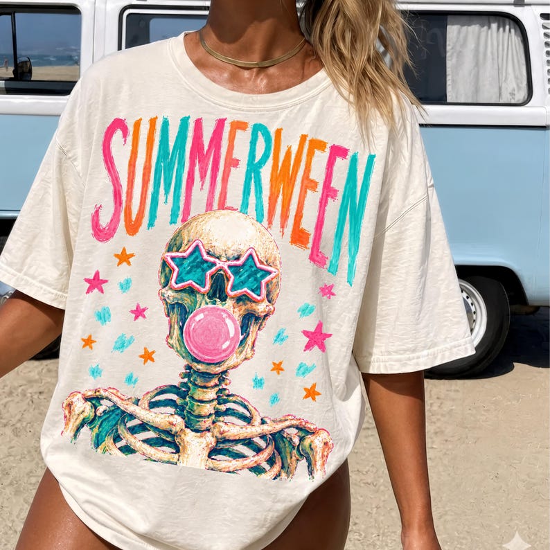 May include: Cream-colored t-shirt with the word "SUMMERWEEN" in bright pink, orange, and teal lettering. The shirt features a skeleton graphic wearing star-shaped sunglasses and blowing a bubblegum bubble. Scattered stars and confetti complete the design.
