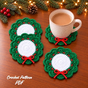 Puede incluir: Tres posavasos redondos de ganchillo con centro blanco, borde festoneado verde y un pequeño lazo rojo. Un posavasos sostiene una taza de cerámica beige con café. El texto "Crochet Pattern PDF" es visible en la esquina inferior izquierda.