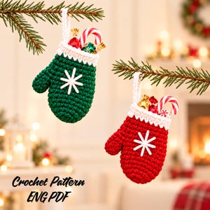 May include: Two small crochet mittens, one dark green and one red, each featuring a white cuff and a white stitched snowflake design. Both mittens have a white hanging loop and contain small wrapped candies and a red and white candy cane.