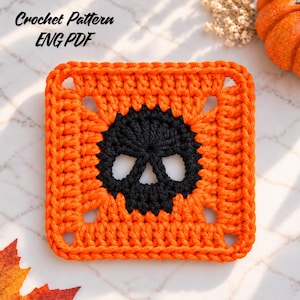 Puede incluir: Un cuadrado de ganchillo con un motivo de calavera negra centrado dentro de un borde de hilo naranja brillante. El texto Crochet Pattern ENG PDF está impreso en negro en la esquina superior izquierda de la imagen, indicando un archivo.