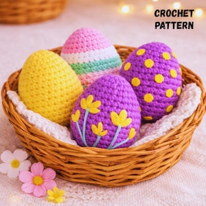 May include: A wicker basket contains four handmade crochet Easter eggs. One is yellow, another pink and white striped, and two are purple with yellow detailing. The text "CROCHET PATTERN" is displayed in black.