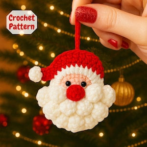 May include: A crocheted Santa Claus ornament with a red hat and beard, held by a hand. The ornament has a white beard and a red nose. The text "Crochet Pattern" is in the upper left corner. The background is a Christmas tree with lights.