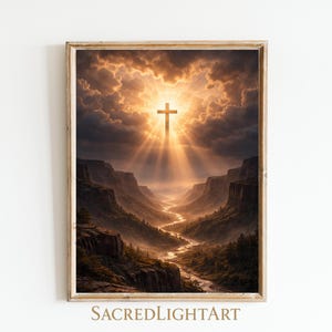 May include: A framed art print depicting a cross illuminated by sunlight breaking through dark clouds. The cross is centered above a canyon landscape with a river winding through it. The artwork is framed in a light brown wooden frame. The text "SACREDLIGHTART" is at the bottom.