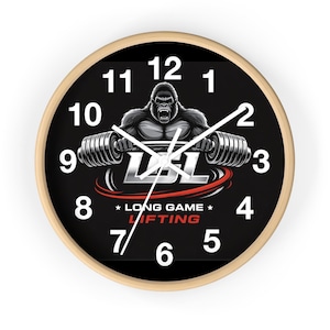 Puede incluir: Reloj de pared redondo con marco de madera clara y esfera negra. El reloj presenta un gorila sosteniendo una barra, el texto "LBL" y "LONG GAME LIFTING". Números y manecillas blancas completan el diseño.