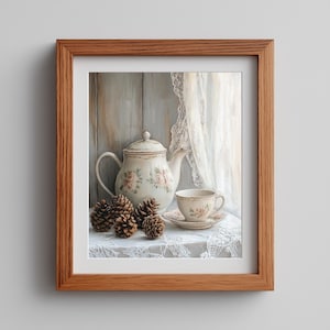 Könnte beinhalten: Gerahmter Kunstdruck eines Stilllebens mit einem Vintage-Teeservice mit floralen Mustern. Das Set umfasst eine Teekanne, eine Tasse und eine Untertasse sowie Tannenzapfen. Der Hintergrund zeigt einen Spitzenvorhang und Holzpaneele.