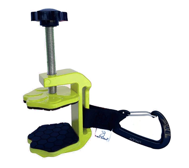 May include: A lime green clamp with a black handle and a black screw. The clamp has a black carabiner clip attached to a black strap. The clamp has a black rubber grip on the bottom and top.
