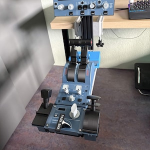 May include: A blue flight simulator throttle quadrant and autopilot control panel featuring black levers, white knobs, and a parking brake lever labelled PARK BRK. The unit is mounted to a desk with a metal clamp and includes various buttons.