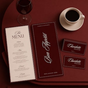 以下が含まれることがあります： クリーム色のメニュー、Bon Appétit、Camille & Daniel、18th August 2026と白文字で書かれた深い赤色のメニューカバー、Charlotte Williamsと書かれた2枚の深い赤色の席札で構成される結婚式のステーショナリーセット。