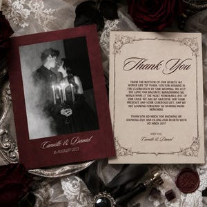 Pu&ograve; includere: Un set di biglietti di ringraziamento per matrimonio composto da un biglietto bordeaux con una foto in bianco e nero di una coppia che tiene delle candele, etichettato Camille & Daniel 16 August 2027, e un biglietto color crema con bordi decorati e il testo Thank You.
