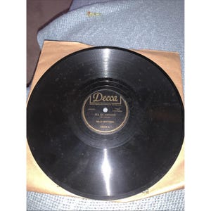 Puede incluir: Un disco de vinilo negro vintage con una funda de papel marrón. La etiqueta del disco dice "Decca" y presenta el título de la canción "I'll Be Around" de The Mills Brothers. El disco está en buen estado.