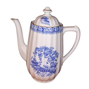 May include: White ceramic coffee pot with a blue floral design. The pot has a ribbed body, a curved spout, and a handle. The lid is topped with a small finial and features a blue design. The pot is likely vintage or antique.