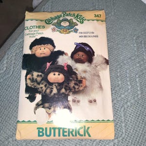 May include: A vintage Butterick pattern envelope featuring Cabbage Patch Kids dolls. The envelope displays three dolls wearing different fur-like outfits. The text "CLOTHES For your Cabbage Patch Kids!" is visible, along with the Butterick logo.