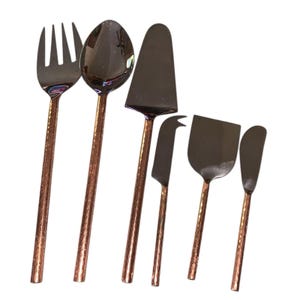 May include: A set of six serving utensils with copper-colored handles and dark metal heads. The set includes a fork, spoon, cake server, cheese knife, spatula, and butter knife. The utensils are arranged on a white background.