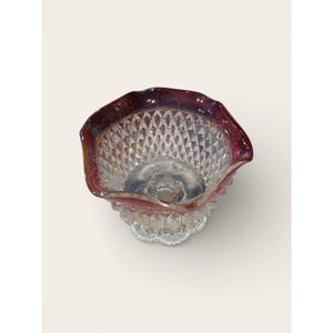 Peut inclure: Un bol en verre transparent avec un motif en losange et un bord festonné de couleur marron. Le bol repose sur une base décorative festonnée. Le verre a une qualité irisée, reflétant plusieurs couleurs.