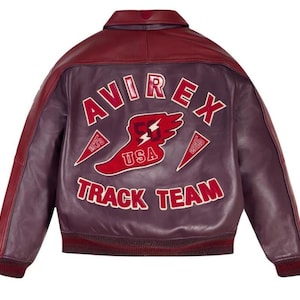 May include: A burgundy leather jacket with a contrasting dark red collar and accents. The back features the text "AVIREX TRACK TEAM" in white lettering, along with a red and white graphic of a running shoe and lightning bolt.