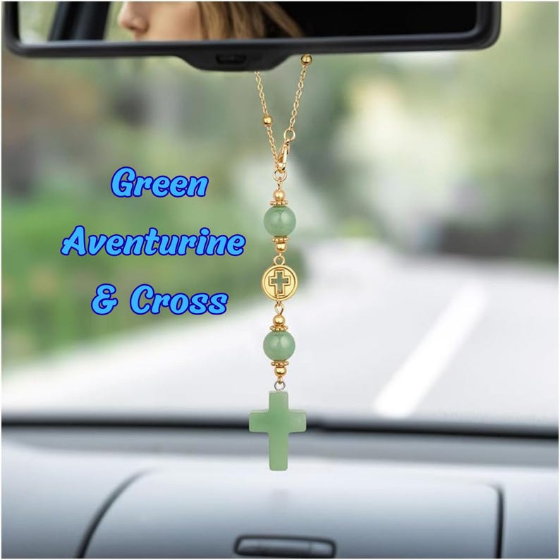 May include: A car rearview mirror hanging ornament featuring a gold-tone chain with two smooth light green aventurine beads, a small circular gold-tone charm with a cross emblem, and a larger light green aventurine cross pendant at the base.
