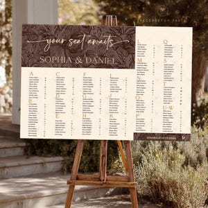 Puede incluir: Un plano de asientos de boda en un caballete de madera. El letrero crema presenta un diseño floral marrón oscuro y el texto "your seat awaits" y los nombres "Sophia & Daniel". Los nombres se enumeran alfabéticamente.