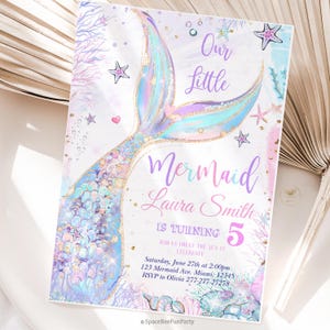 Puede incluir: Una invitación con temática de sirena con una cola de sirena brillante en tonos azules, morados y dorados. La invitación incluye el texto "Our Little Mermaid" y detalles para una fiesta de cumpleaños, incluido el nombre Laura Smith y la edad 5.