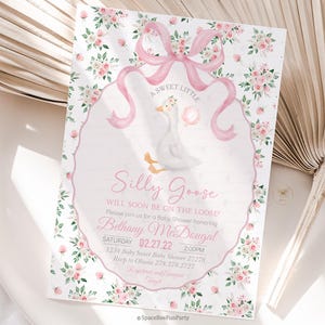 May include: A baby shower invitation with a watercolour design. The invitation features a white goose holding a pink balloon, surrounded by pink flowers and a pink ribbon. Text includes "Silly Goose" and event details.