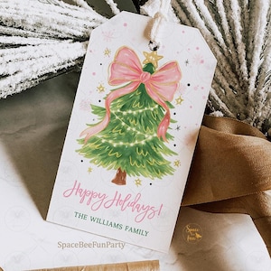 Puede incluir: Una etiqueta de regalo blanca con un diseño de árbol de Navidad en acuarela. El árbol es verde con un lazo y una cinta rosas, y una estrella dorada. La etiqueta dice "Happy Holidays!" y "The Williams Family". El logotipo de SpaceBeeFunParty está en la esquina inferior derecha.