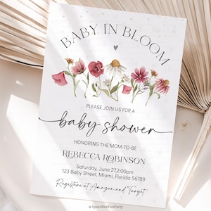 May include: Baby shower invitation with floral watercolor design. The invitation reads "Baby in Bloom" and includes details for Rebecca Robinson's baby shower. The invitation features a floral arrangement of red, pink, and white flowers.