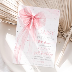 Puede incluir: Una tarjeta de invitación rosa y blanca para una fiesta de primer cumpleaños. La tarjeta presenta un gran lazo rosa transparente y el texto "DAISY IS TURNING one". La invitación incluye la fecha, la hora y el lugar de la fiesta.