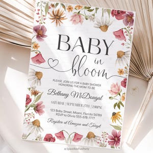 May include: A baby shower invitation with the words "BABY in bloom" in black script. The invitation is decorated with watercolor flowers in shades of pink, red, and yellow. The invitation includes the name Bethany McDougal, date, time, and location.