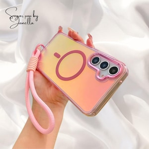 Puede incluir: Una funda transparente para teléfono con un diseño degradado rosa y amarillo, con un círculo rosa y tres lentes de cámara. Incluye una correa de muñeca rosa y el texto "Sugar pop by Janella".
