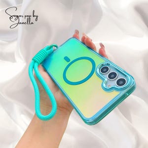 May include: A clear phone case with a green and yellow gradient, and a turquoise loop strap. The case has a circular design and three camera lenses. The text "Sugar pop by Janella" is in the upper left corner.