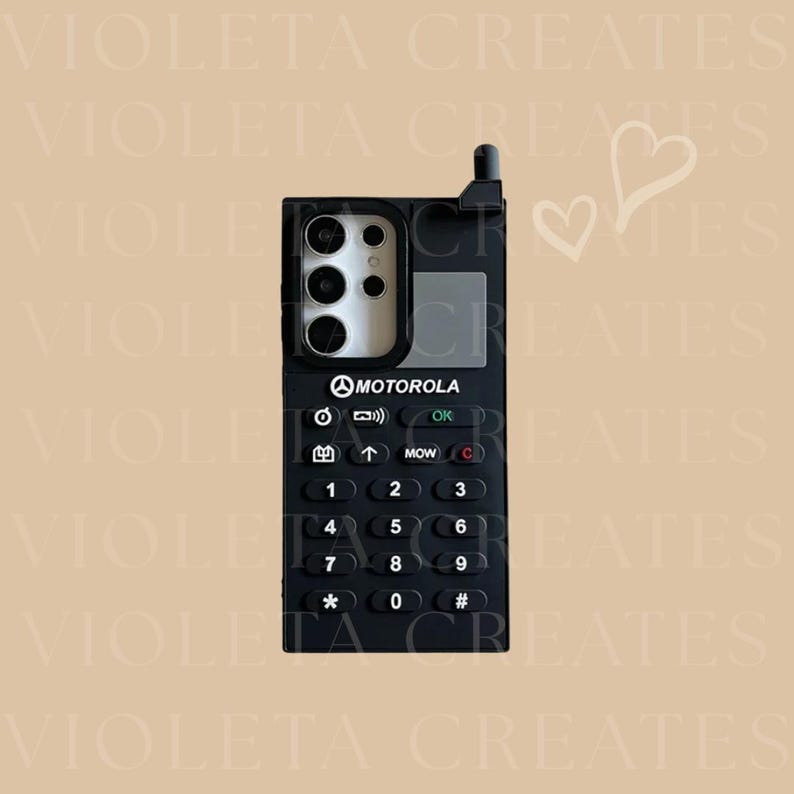 May include: A black phone case with a retro Motorola design. The case features a keypad with numbers and symbols, a camera cutout, and the Motorola logo. The design includes an antenna and a small screen area.