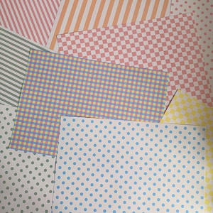 Könnte beinhalten: Eine Sammlung von gemusterten Papieren mit verschiedenen Designs, darunter rosa-weiße Streifen, orange-weiße Streifen, rosa-weiße Karomuster, grün-weiße Streifen, blau-gelbe Karos, gelb-weiße Karos und blaue Punkte auf weißem Grund.