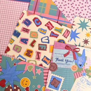 May include: A collection of patterned papers featuring various designs including colourful torn-paper style letters, blue and yellow starbursts, pink polka dots, plaid, grid patterns, and a cafe receipt graphic with a bear illustration and red bows.