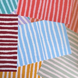May include: A collection of rectangular paper sheets featuring various colour combinations with a repeating pattern of vertical or diagonal stripes. Each sheet displays a distinct two-tone design with jagged, hand-drawn style lines in colours including red, blue, yellow, green, and purple.