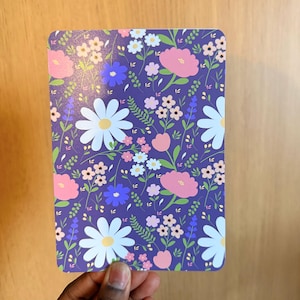 May include: A set of three ceramic mugs with a speckled, cream-colored glaze. Each mug features a different hand-painted floral design in shades of blue, green, and yellow. The mugs have a simple, rounded shape and a comfortable handle.