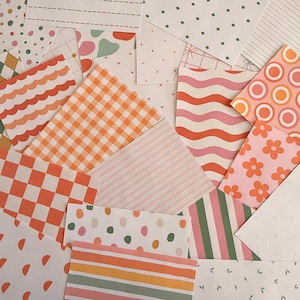 May include: An assortment of patterned paper sheets in diverse designs and colours. Patterns include gingham, stripes, polka dots, flowers, and wavy lines. Colours include orange, pink, green, and white. The sheets are arranged in a layered, overlapping composition.