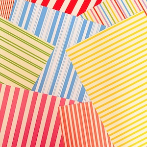 Op de afbeelding: Een verzameling overlappende rechthoekige vellen papier met diverse streeppatronen in levendige kleuren, waaronder rood, geel, blauw, groen, oranje en roze. Elk vel toont verschillende verticale of diagonale lijnontwerpen.