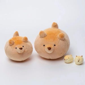 Puede incluir: Una colección de juguetes de peluche con forma de oso de varios tamaños. Los osos son principalmente de color marrón claro con detalles marrones oscuros en las orejas y la nariz. Dos osos redondos más grandes están acompañados de dos juguetes de oso redondos más pequeños.