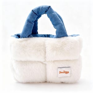 Könnte beinhalten: Eine kleine, weiße Kunstfell-Tragetasche mit einem gesteppten Design. Die Tasche hat einen jeansblauen Griff und Besatz. Ein kleines rechteckiges Etikett mit dem Text "Yamitafab" ist auf der Vorderseite der Tasche aufgenäht.