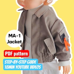 Puede incluir: Una chaqueta MA-1 color canela con un cuello alto blanco y pantalones blancos. La chaqueta tiene un bolsillo en la manga con una cinta naranja. El texto en la imagen dice "MA-1 Jacket", "PDF pattern", "STEP-BY-STEP GUIDE" y "18MIN YOUTUBE VIDEOS".