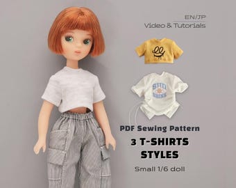 May include: A doll with short ginger hair wearing a white t-shirt and grey pinstriped cargo pants. Beside the doll are two small t-shirts, one mustard yellow with a black graphic and one white with a blue graphic. Text reads: PDF Sewing Pattern 3 T-SHIRTS STYLES Small 1/6 doll.