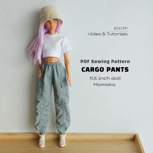 May include: A doll with long purple hair wearing a beige bucket hat, a white crop top, and gray cargo pants with white sneakers. Text reads: EN/JP Video & Tutorials, PDF Sewing Pattern CARGO PANTS, 11.5 inch doll, Momoko.