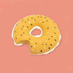 May include: A yellow donut with a bite taken out, featuring white frosting and black and white sesame seeds. The donut is set against a solid coral background, creating a playful and appetizing visual.